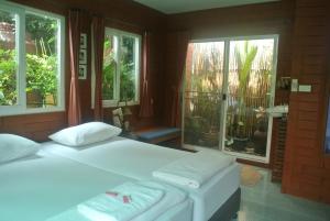 a bedroom with two beds and two windows at P.Y. Guest House in Kanchanaburi