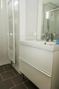 a white bathroom with a sink and a mirror at Chaletparc Krabbenkreek Zeeland - Chalet 94 in Sint Annaland