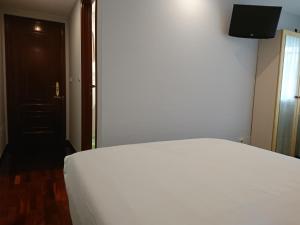 a bedroom with a white bed and a television at Saudade Hostal Cafetería in A Coruña