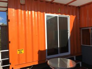 an orange shipping container with a table and a window at Amsterdam lofts 4 in Poços de Caldas