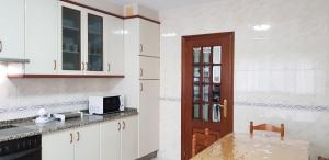 eine Küche mit weißen Schränken und einem Tisch mit einer Mikrowelle in der Unterkunft Edificio Zoqueiro in San Cosme de Barreiros