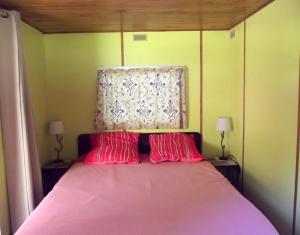 a bedroom with a pink bed with two red pillows at Mobil-home in Ravières