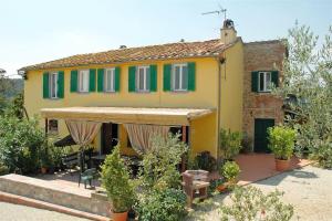 a yellow house with green shuttered windows and plants at La Piaggia in Altopascio