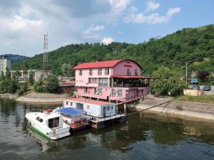 a pink house and boats docked in a river at Pensiunea Taka in Orşova