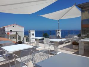 a patio with tables and chairs and an umbrella at La Casa di Gino in San Nicola