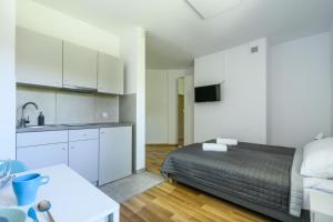 sypialnia z łóżkiem oraz kuchnia z białymi szafkami w obiekcie Art Apartments w Warszawie