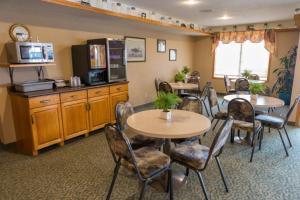 a dining room with tables and chairs and a kitchen at Woodland Inn in Meadow Lake