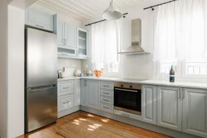 a kitchen with white cabinets and a stainless steel refrigerator at Asterias house, Skopelos in Skopelos Town