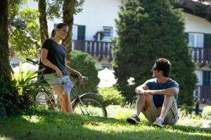 Ein Mann und eine Frau sitzen im Gras mit einem Fahrrad in der Unterkunft Hotel Toriba in Campos do Jordão