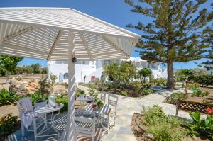 un ombrellone bianco su un patio con sedie e tavolo di Maroussa Studios ad Agia Anna Naxos