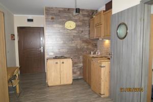 a kitchen with wooden cabinets and a clock on a brick wall at Apartament Bosmański in Puck