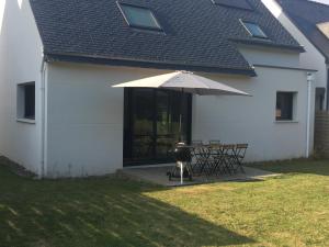 a grill and an umbrella next to a house at Maison Jardin De La Baie in Douarnenez