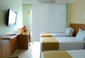 um quarto de hotel com duas camas e uma televisão de ecrã plano em Real Classic Hotel em Aracaju