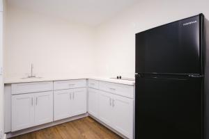 a kitchen with a black refrigerator and white cabinets at Palace Inn- Louetta in Spring