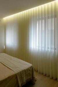 a bedroom with a bed and a window with white curtains at Apartment Trindade Way in Porto