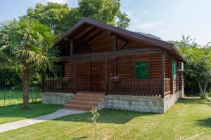 a log cabin with a porch and a palm tree at Wooden Village Resort in Ponari
