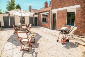 a patio with a grill and chairs and an umbrella at LA VILLA JEAN-BART in Saint-Valéry-sur-Somme
