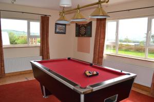 uma mesa de bilhar vermelha num quarto com janelas em Sally's Vineyard em Buncrana