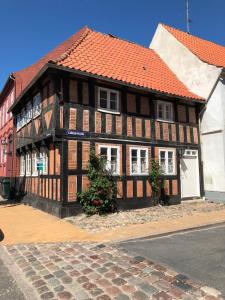a brown and white building with a red roof at Madam Bundsens Huse in Assens
