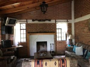 a living room with a fireplace in a brick wall at Cabañas las Alazanas in Mazamitla