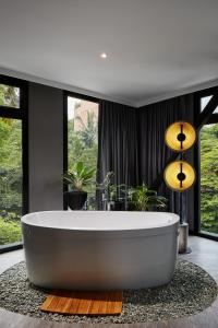 uma banheira na casa de banho com janelas em The Click Clack Hotel Medellín em Medellín