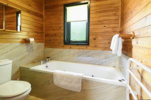 a bathroom with a bath tub and a toilet at Woodlands Hotel & Pine Lodges in Grange Over Sands