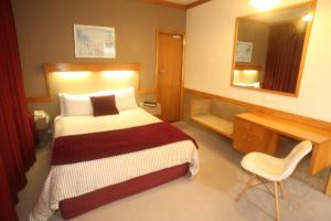 a bedroom with a bed and a desk and a mirror at The Grand Hotel Wanganui in Whanganui