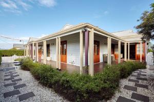 a white house with a porch and a yard at Highview House Hunter Valley in Cessnock