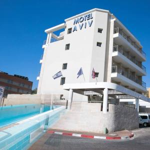 un hotel con piscina frente a un edificio en Motel Aviv en Eilat