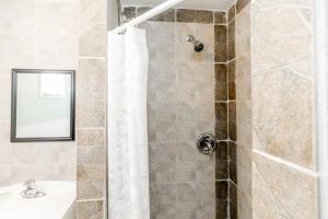 a bathroom with a shower with a sink and a mirror at Beachfront at Beach1 Motel in Wasaga Beach