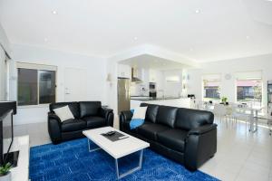 a living room with two black couches and a table at Blue Zone - Aldinga Beach - C21 SouthCoast Holidays in Aldinga Beach