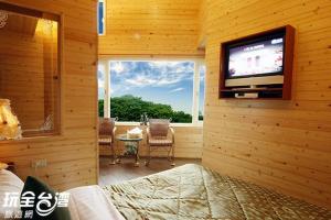 um quarto com uma televisão numa parede de madeira em House of Ahan em Meishan