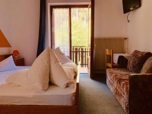 a hotel room with a bed and a couch and a window at Laugen Cafè, Pizza, B&B in San Felice