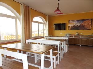 a dining room with yellow walls and white tables and chairs at Casa Venere in Lampedusa