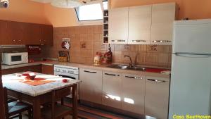 eine Küche mit einem Tisch und einem weißen Kühlschrank in der Unterkunft La casa di Beethoven in Acquarica del Capo