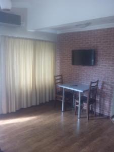 Habitación con mesa con sillas y TV en una pared de ladrillo. en malu en Kutaisi