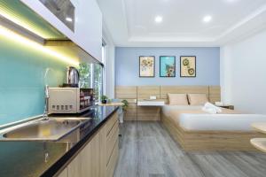 een slaapkamer met een bed en een keuken met een wastafel bij Cozrum Homes Citi Town in Ho Chi Minh-stad