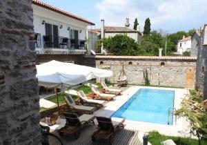a pool with chairs and an umbrella and a house at Küçükköy Otel in Ayvalık