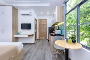 a bedroom with a bed and a table and a kitchen at Cozrum Homes Citi Town in Ho Chi Minh City