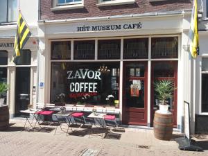 una tienda frente a una cafetería con mesas y sillas en B&B Museumkwartier Schiedam en Schiedam