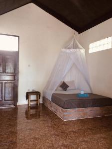 a bedroom with a bed with a mosquito net at Pantai Paris Homestay in Maumere