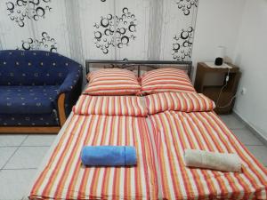 アバッザロークにあるNorbi Apartmanokのベッド1台(枕2つ、ソファ付)