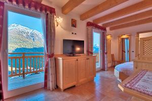 a bedroom with a bed and a television and a balcony at Albergo San Rocco in Peio