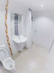 a white bathroom with a toilet and a sink at Hostbox Bangkok in Bangkok