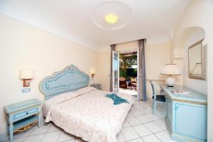a bedroom with a bed and a desk and a table and a mirror at Villa Formica in Ischia