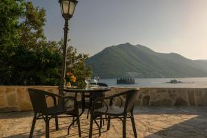 a table with two chairs and a lamp with a view of the water at Villa & Apartments Perasto in Perast