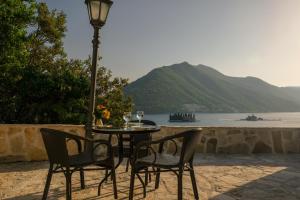 uma mesa com duas cadeiras e um candeeiro com vista para a água em Villa & Apartments Perasto em Perast