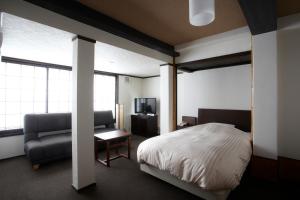 ein Schlafzimmer mit einem Bett, einem Sofa und einem Stuhl in der Unterkunft Koyado Enn in Toyooka