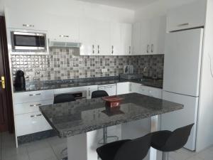 eine Küche mit weißen Schränken und einer Granitarbeitsplatte in der Unterkunft Bungalow Playa Bastian - Piscina climatizada - Wifi - Playa 1 min. in Costa Teguise