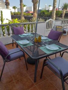 einen Tisch mit Stühlen und Gläsern auf der Terrasse in der Unterkunft Bungalow Playa Bastian - Piscina climatizada - Wifi - Playa 1 min. in Costa Teguise